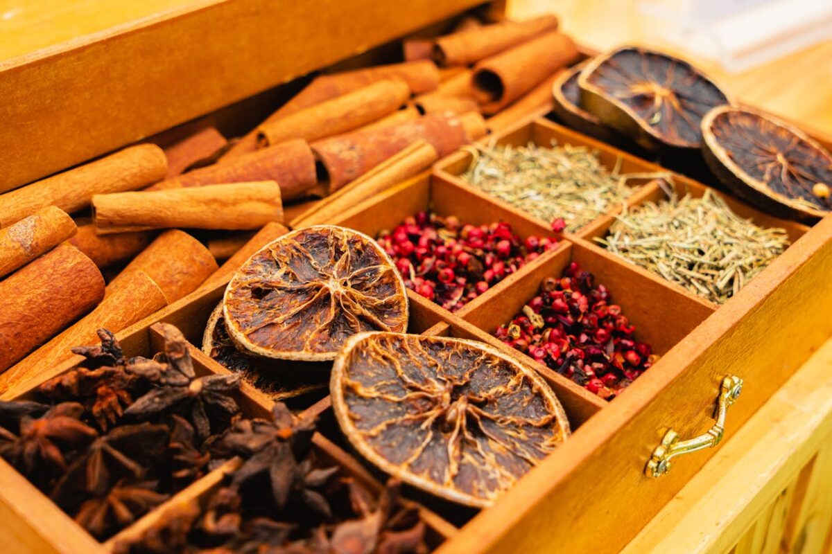 A wooden box filled with assorted spices and dried citrus slices, showcasing natural flavors.