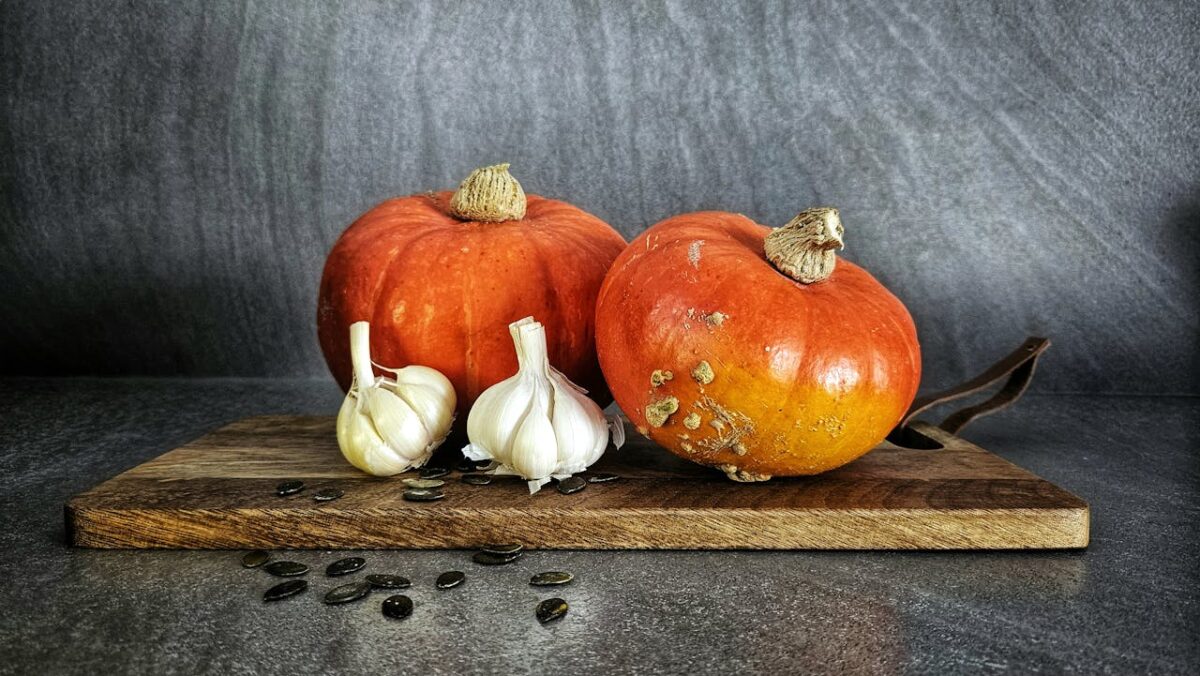 A rustic still life featuring pumpkins and garlic, highlighting autumn harvest and culinary themes.