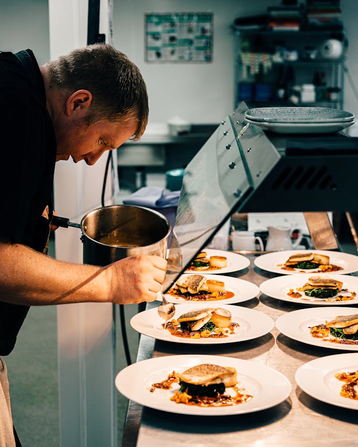 A chef meticulously plating gourmet dishes in a professional kitchen setting in London.